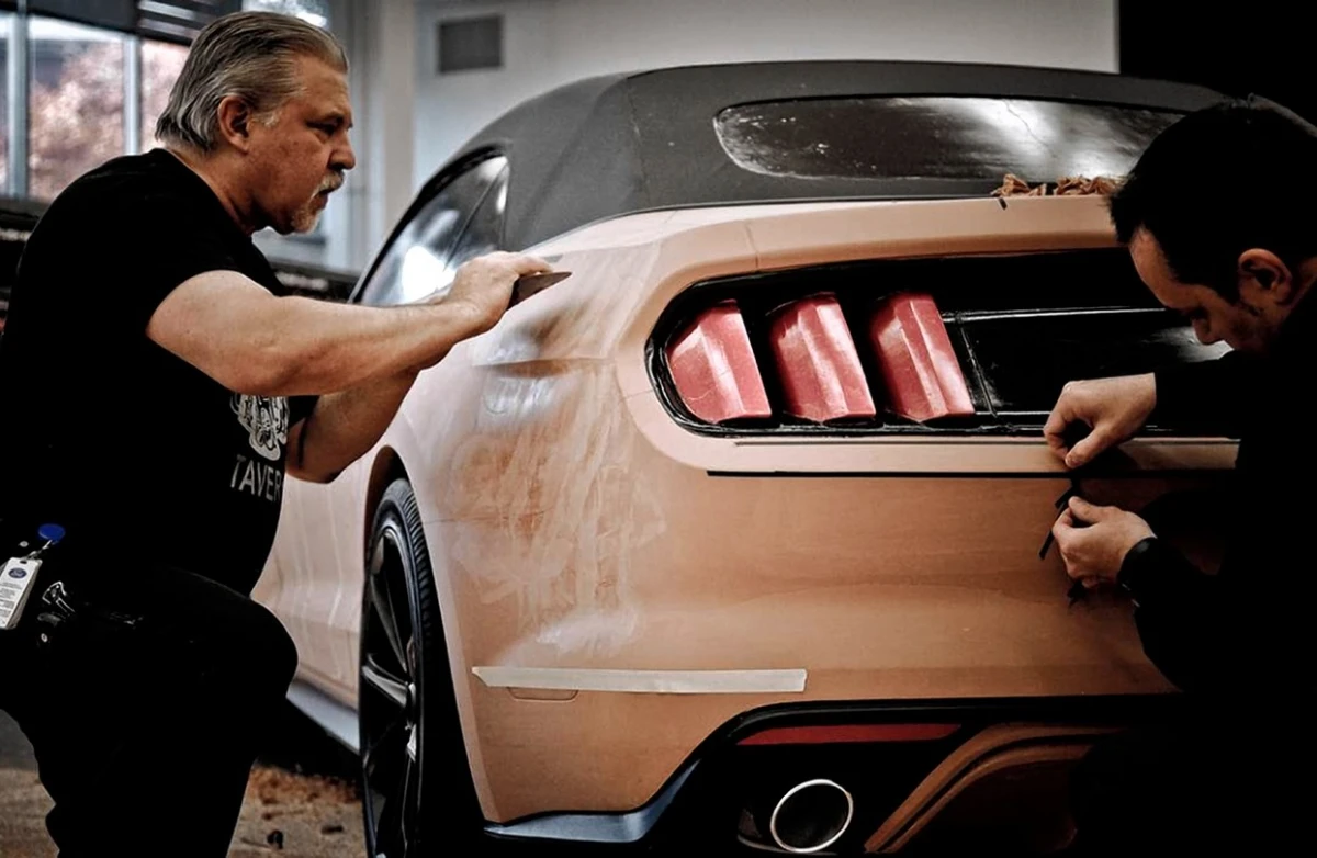 A modeller refining a clay surface by hand with a steel scraper